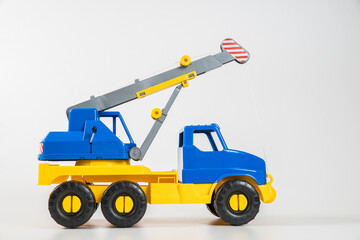 Plastic car. Toy model isolated on a white background. Yellow-blue truck crane with an arrow to lift the load.