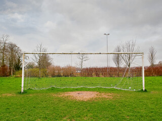 Football goal post on a training ground. Worn out grass on a keeper spot. Soccer theme background