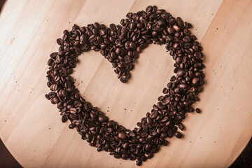 Coffee beans in a heart shape on a wooden board. Top view.