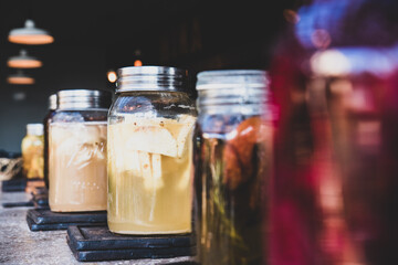 Glass jars with colorful foods and drinks lined up on a bar in a restaurant in Tulum