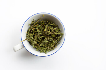 Dry stevia leaves in white cup on white
