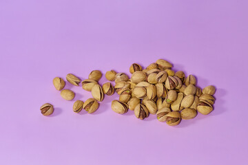 Portion of salted open pistachios on a plain lilac background
