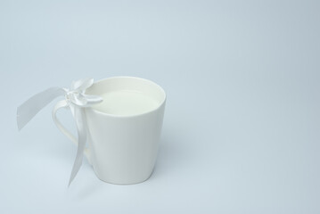 White cup of milk with a bow on a white background