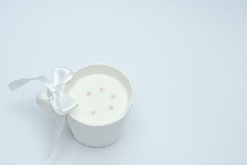 White cup of milk with a bow on a white background