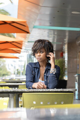 woman with short hair waiting sitting in front of a table in a restaurant outside, wearing makeup and casual clothes, lifestyle in the city