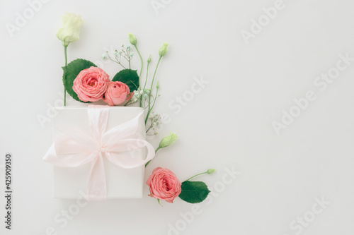 Mother's day card, pink background with white flowers and a present postcard gift, flatlay copyspace background