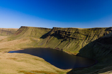 Fototapeta na wymiar A beautiful lake at the foot of steep-sided mountains (Llyn y Fan Fach, Brecon Beacons, Wales)