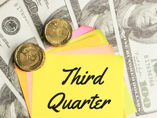 Business and finance concept. Phrase Third Quarter written on sticky note with fake money and coins.