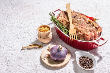 Raw pork roll stuffed with garlic and carrots in a ceramic roasting dish