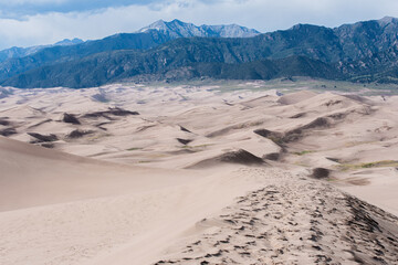 massive mountain peaks behind miles of epic sand dunes