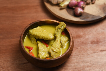 Gulai ayam ,a popular dish of chicken curry from indonesia .served in wooden bowl ,isolated wooden background