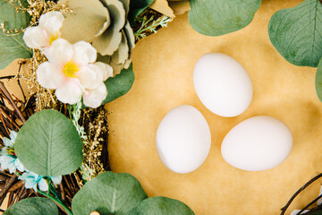 easter eggs with flowers. 3 white eggs next to a green wreath. Spring is coming. Easter eggs with green branches. Bird's nest	