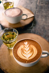 Cup of latte art coffee and hot tea on wooden table