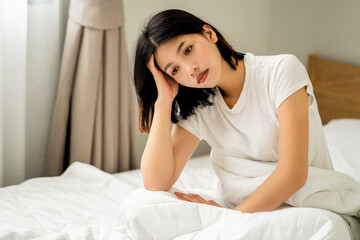 Young women feeling headaches and unhappy on bed, female suffering from migraine.