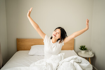 young woman wakes up with stretching exercise on a bed at morning time, lifestyle female holiday.