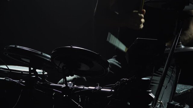 Professional musician playing drums and percussion cymbals in a dark smoky studio with lights. Close up of the drummer torso pounds on the drum kit. Rock concert, live performance. Silhouette.