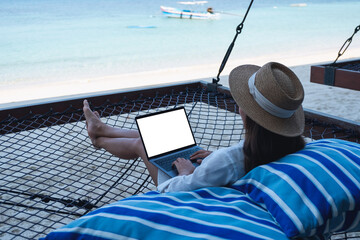 Mockup image of a woman using and typing on laptop computer with blank desktop screen while lying...
