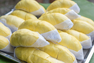 The golden yellow durian is placed on a stainless steel tray with a banana leaf background. Ripe durian, the king of fruits of Thailand