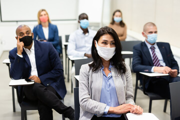 Group of business people in protective masks of different nationalities at business seminar