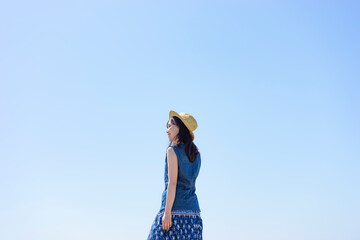 振り向く麦わら帽子を被った日本人女性と青空