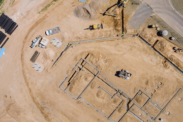 View of a large construction site where earthmoving equipment the ground to lay pipes residential buildings.