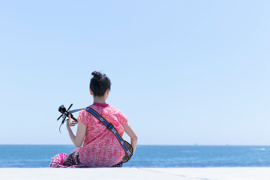 海を見ながら三線を弾く日本人女性