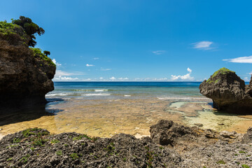 Naklejka premium Beautiful hidden beach with gradient blue clear water full of corals, blue sky, rock formation typical of Okinawa. Iriomote Island.