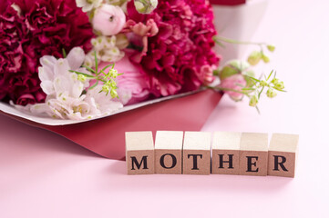 A bouquet of flowers and a block of text for mother placed on a pink background