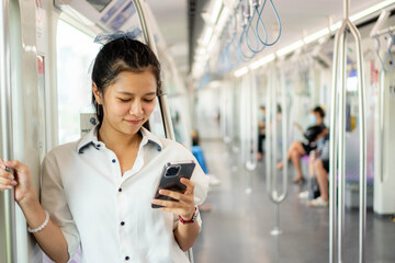 Young beautiful girl using smart phone inside empty subway or sky train car, leisure and daily life, Social media concept.