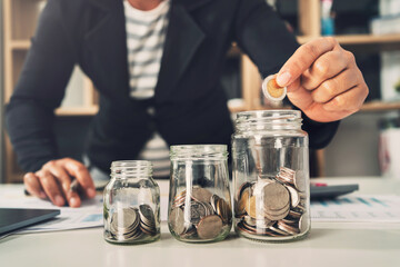 saving money with hand putting coins in jug glass concept financial