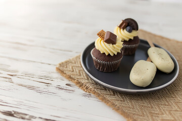 Muffins and cupcakes on tray. Cookie ice creams on a stick. Wooden background