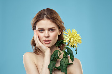 beautiful woman with yellow flower near face smiling cropped view portrait of bared shoulders