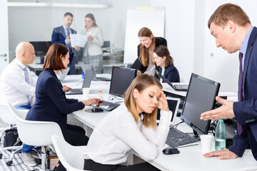 Outraged angry unhappy manager expressing dissatisfaction with work of frustrated young pleasant woman in modern office