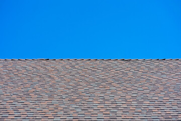 Laminated architectural roof shingles of different shapes and sizes give the rooftop dimensional appearance. Blue sky
