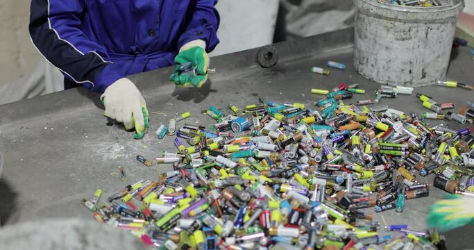 View of the hands of a person in gloves sorting used batteries. Recycling and sorting. Environmental protection concept.