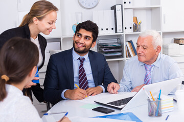 Obraz premium Employees are writing financial reports and discussing with mature boss in the office.