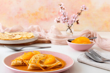 Pancakes Suzette, French traditional desert. Pancakes with oranges. White wooden table with blue fabric. Top down view.