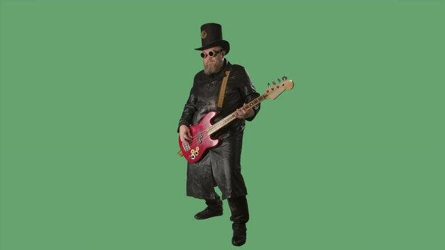 A bearded man in a long leather coat, an Irish style hat and original glasses plays the red guitar. Rock musician plays bass guitar in studio on green screen chroma key. Slow motion.