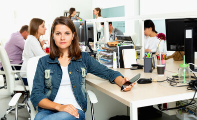 Portrait of young glad cheerful positive female freelancer confidently smiling at workplace in coworking space