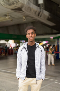 Portrait of handsome black African man with cool attitude at skytrain station in Bangkok