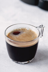 Fresh hot espresso in a transparent glass cup. Black coffee on stone background. Vertical - Image