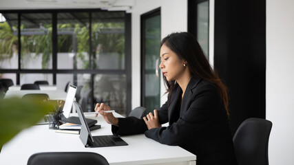 Side view of serious businesswoman working with computer tablet in modern office.