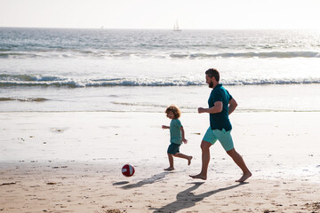 Father and son play soccer or football on the beach. Dad and child enjoying outdoor. Lifestyle and family vacation, happiness men concept.
