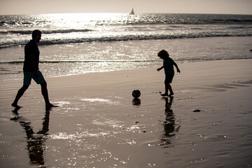 Fototapeta na wymiar Father and son play soccer or football on the beach.