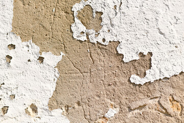 Old grunge background with white peeling plaster on stone wall 