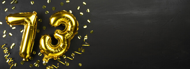 golden foil balloon number seventy three. Birthday or anniversary card with the inscription 73. Black concrete background. Anniversary celebration. Banner.