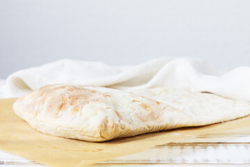 Homemade white tortilla lies on parchment, on flour leaven.