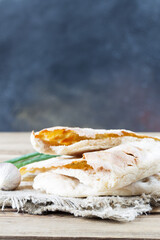 The broken pita bread on a flour sourdough lies on a plate, together with green onions and garlic. Fermented food.