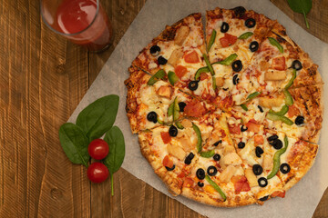 Delicious appetizing whole pizza with sweet green pepper, chicken, cheese and tomatoes on a wooden background, top view. Popular food all over the world.