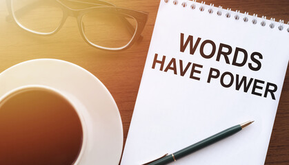 WORDS HAVE POWER - text on paper with cup of coffee and glasses on wooden background in sinlight.